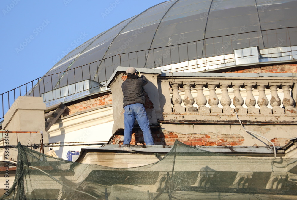 Guest worker on the roof of a renovated house, Nevsky Prospekt, St. Petersburg, Russia, October 2022