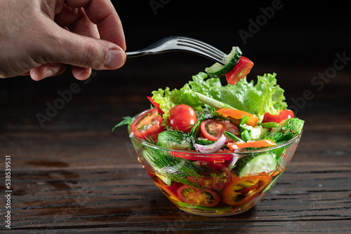 Canvas-taulu Vegetable salad with leafy greens in the glass oil is on the wooden table