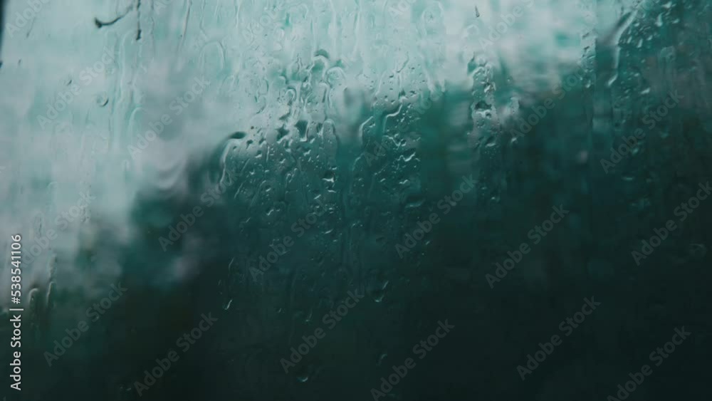 raindrops run down the glass when it rains. rain falling outside the window. raindrops close up. wet glass with drops running down it.