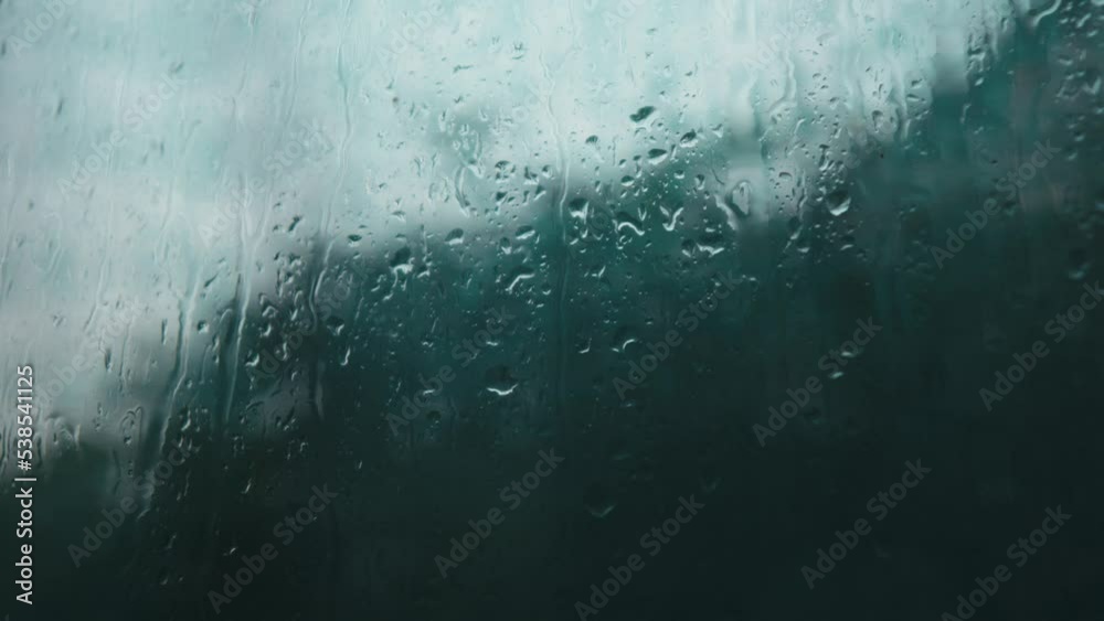 raindrops run down the glass when it rains. rain falling outside the window. raindrops close up. wet glass with drops running down it.