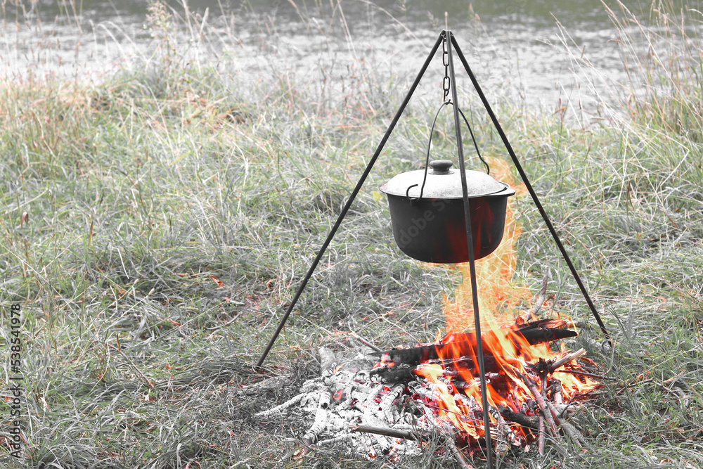 cooking delicious tasty food outdoors on fire in iron pot in summer in good weather with wood from forest cooking delicious tasty food outdoors on fire in iron pot in summer in good weather with wood from forest