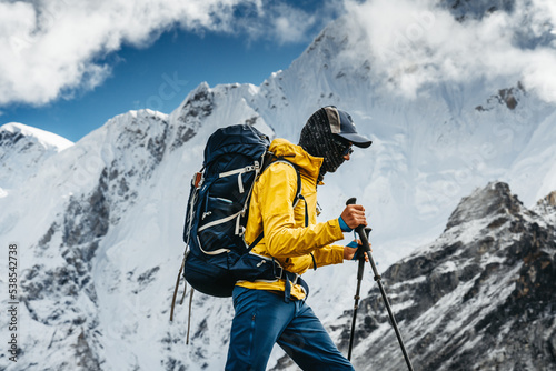 Brave tourist climb on altitude cloudy mountains. Solo traveler wearing professional backpack standing in front of high mountain