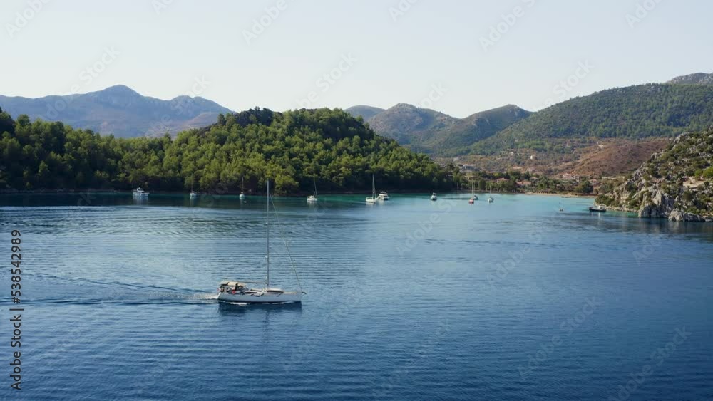 Aerial view of yacht with solar panels navigating on water of Cennet bay, located in Selimiye village of Marmaris District, Turkey. Alternative energy source vessel going sailing. Aerial view of yacht with solar panels navigating on water of Cennet bay, located in Selimiye village of Marmaris District, Turkey. Alternative energy source vessel going sailing.