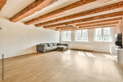 Table with chairs and flowers located near lounge area and kitchen in spacious room of contemporary apartment