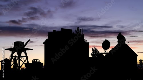 Gost Town of El Dorado, Time Lapse at Twilight with Abandoned Vintage Water Tower, cars and buildings in Silhouette, Nelson, Nevada, USA photo