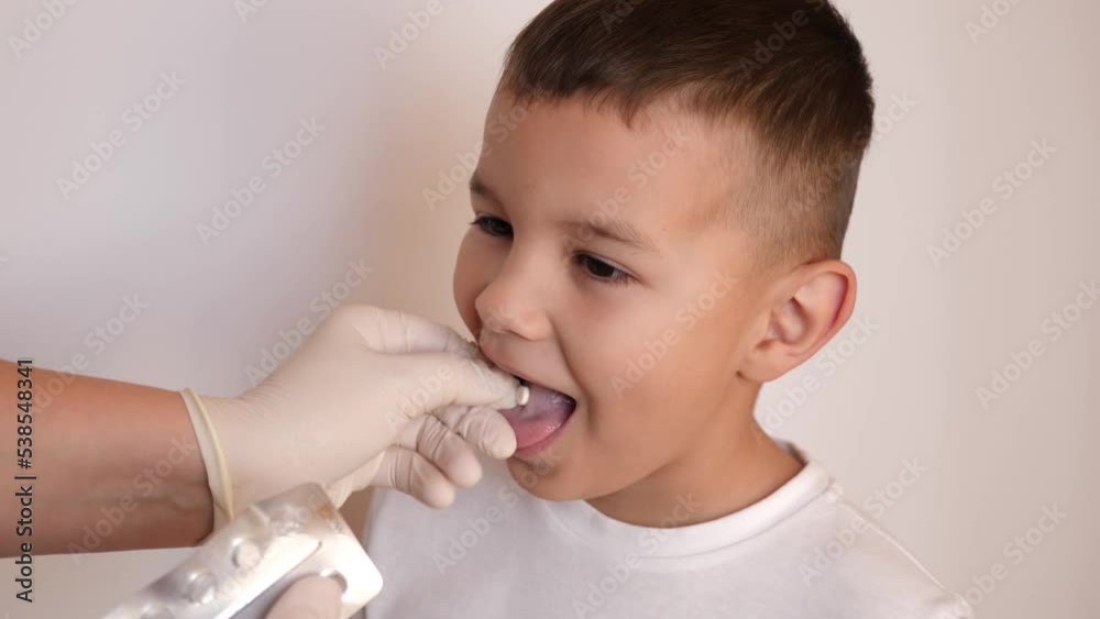A little boy is given a throat lozenge. A little boy is given a throat lozenge.