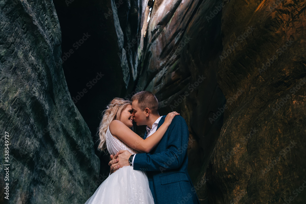 Bride and groom on the background of rocks. the man gently kisses the girl.