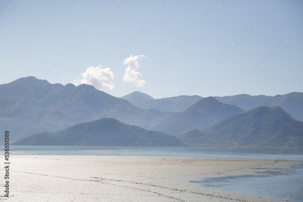 Silhouettes of mountains on Skadar lake in the haze in the morning.