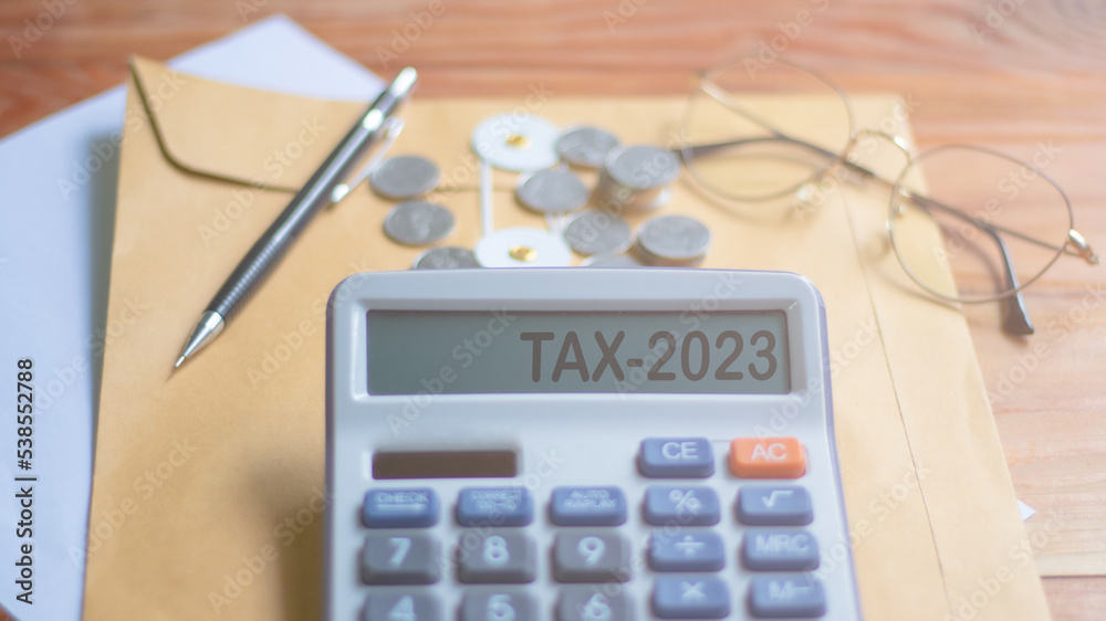 Word Tax 2023 on the calculator business ideas and taxes Calculator, currency, books, tax forms and vanta pen on wooden table Word Tax 2023 on the calculator business ideas and taxes Calculator, currency, books, tax forms and vanta pen on wooden table