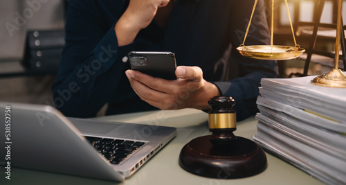 justice and law concept.Male judge in a courtroom  the gavel, working with smart phone and laptop and digital tablet computer on wood table in morning light .