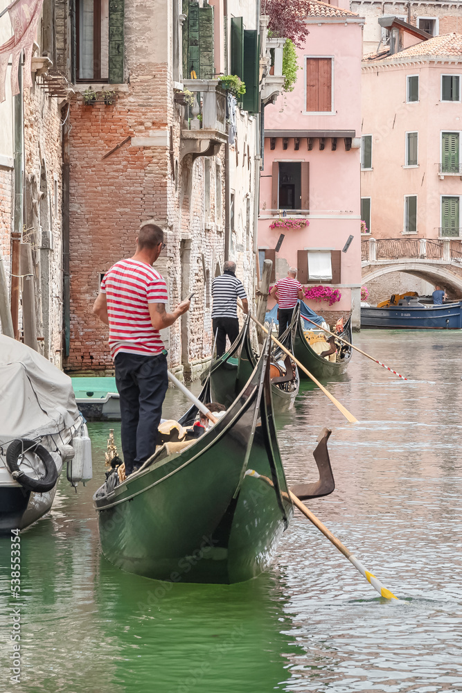 Gondoliers et leur gondole sur un canal dans Venise.