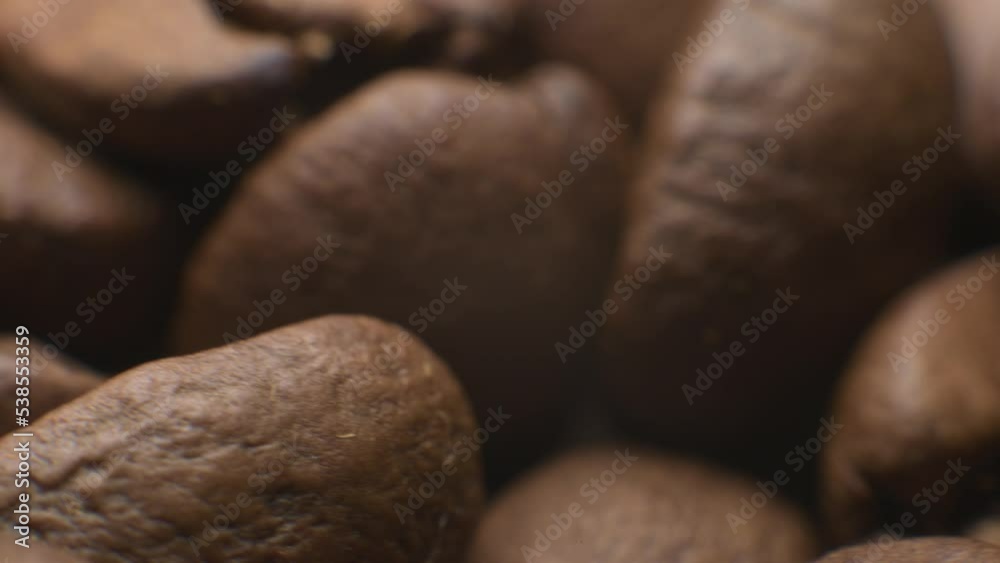Extreme macro close-up set of coffee beans after roasting in a coffee shop in a wooden cup on a black background, rotating in the dark. High dynamic range