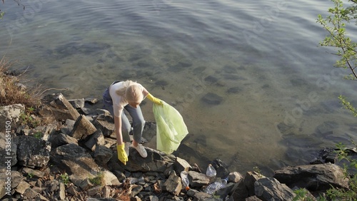 Photos A woman removes rubbish among the stones near the lake