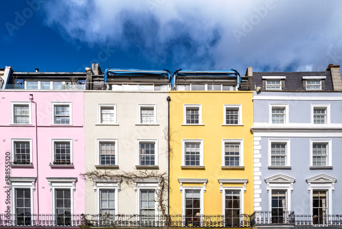 Colourful terraced townhouses with summer sky background. The area of Notting Hill, London, is famous for streets of houses with brightly painted exteriors.
