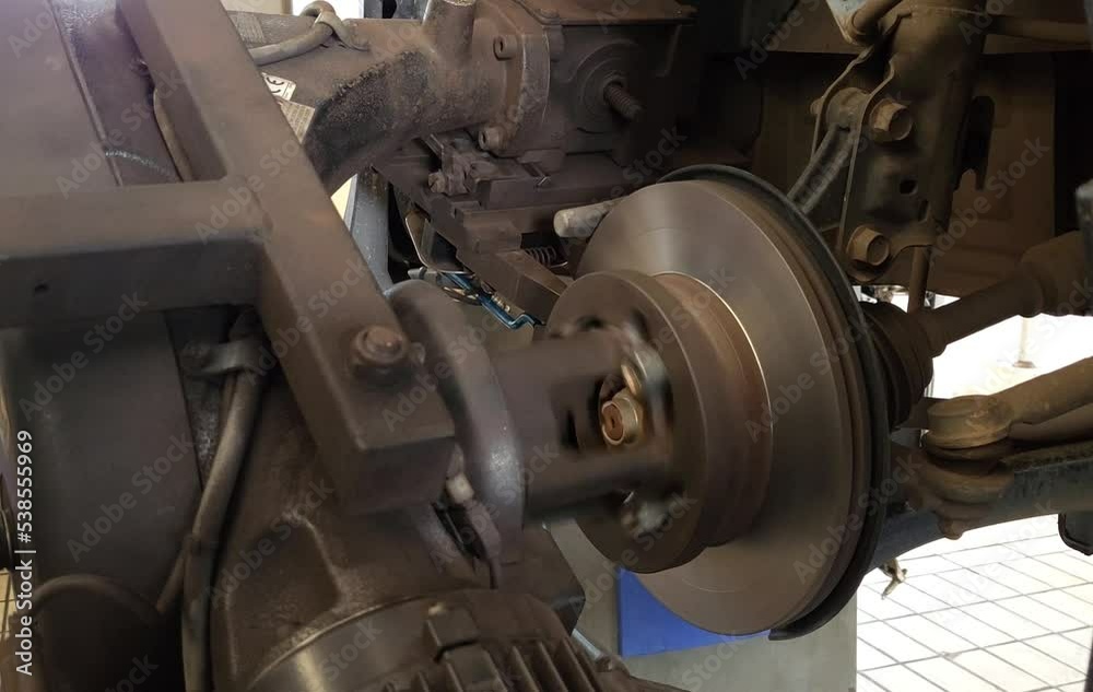 Brake repair mechanics use a lathe to polish a car's brake disc without