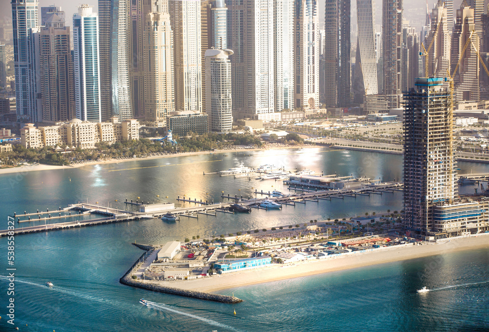 Obraz premium Dubai Marina skyscrapers complex of residential and office buildings at sunset. Yachts and speed boats in the gulf water. Dubai, UAE