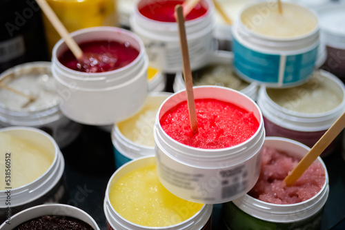 Set of jars with natural body  face scrub with wooden stick on counter of cosmetic store. Treatment  care and wellness concept