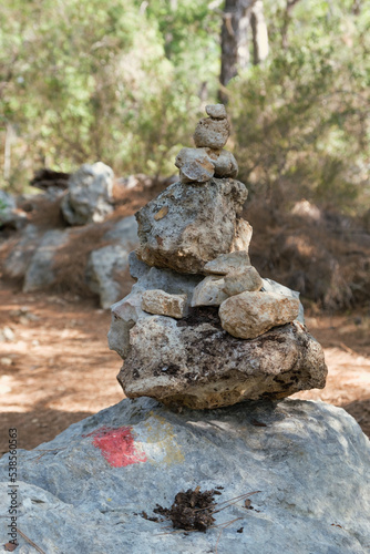 Trail Cairn in a forest indicating a trekking route for tourists. Marking the tourist route on the stones for navigation. Pile of stones used as hiking marker, next to a hiking trail sign