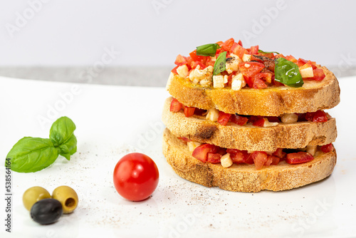 Primo piano di bruschetta cibo italiano con pomodori, basilico, olio pepe e olive caldi colori estivi photo