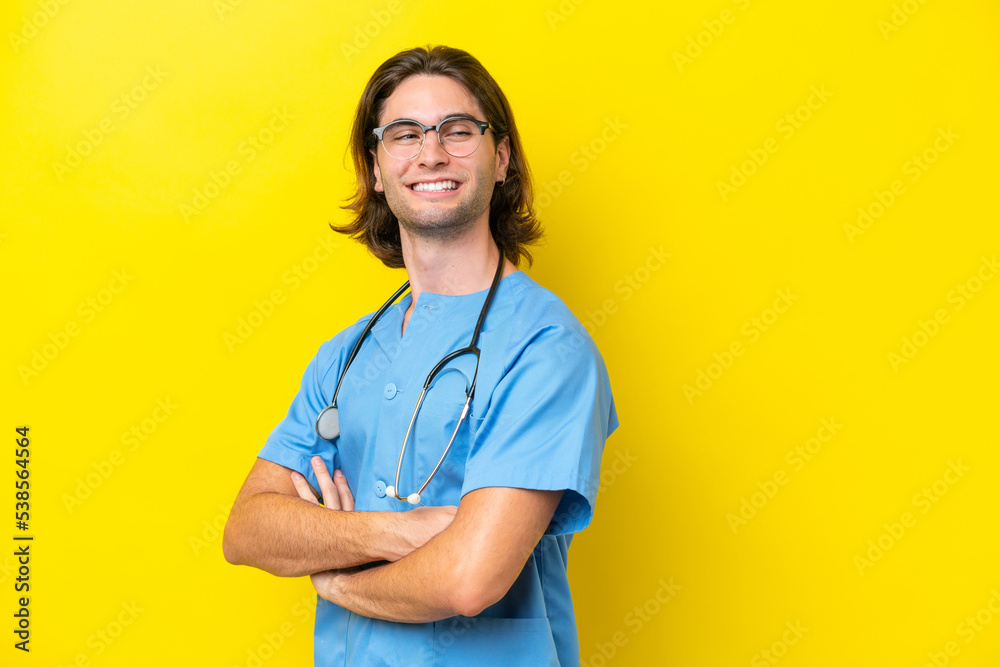 Young surgeon caucasian man isolated on yellow background with arms crossed and happy Young surgeon caucasian man isolated on yellow background with arms crossed and happy