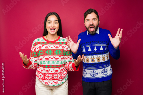 Excited couple with ugly sweaters receiving a surprise on christmas © AntonioDiaz