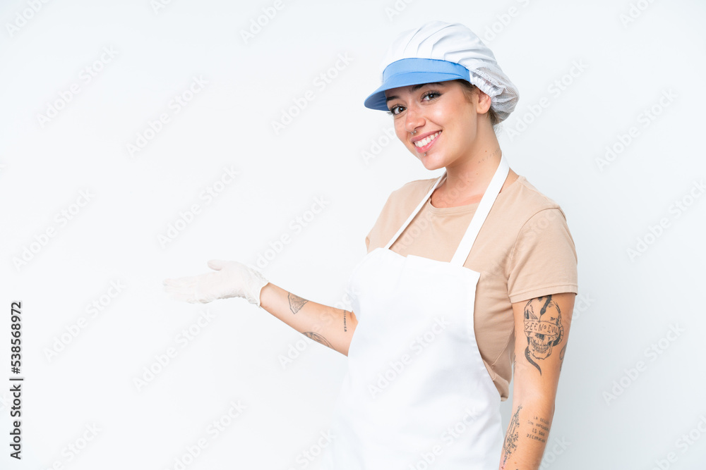 Fishmonger wearing an apron and holding a raw fish isolated on white background extending hands to the side for inviting to come Fishmonger wearing an apron and holding a raw fish isolated on white background extending hands to the side for inviting to come