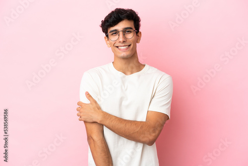Young Argentinian man isolated on pink background laughing