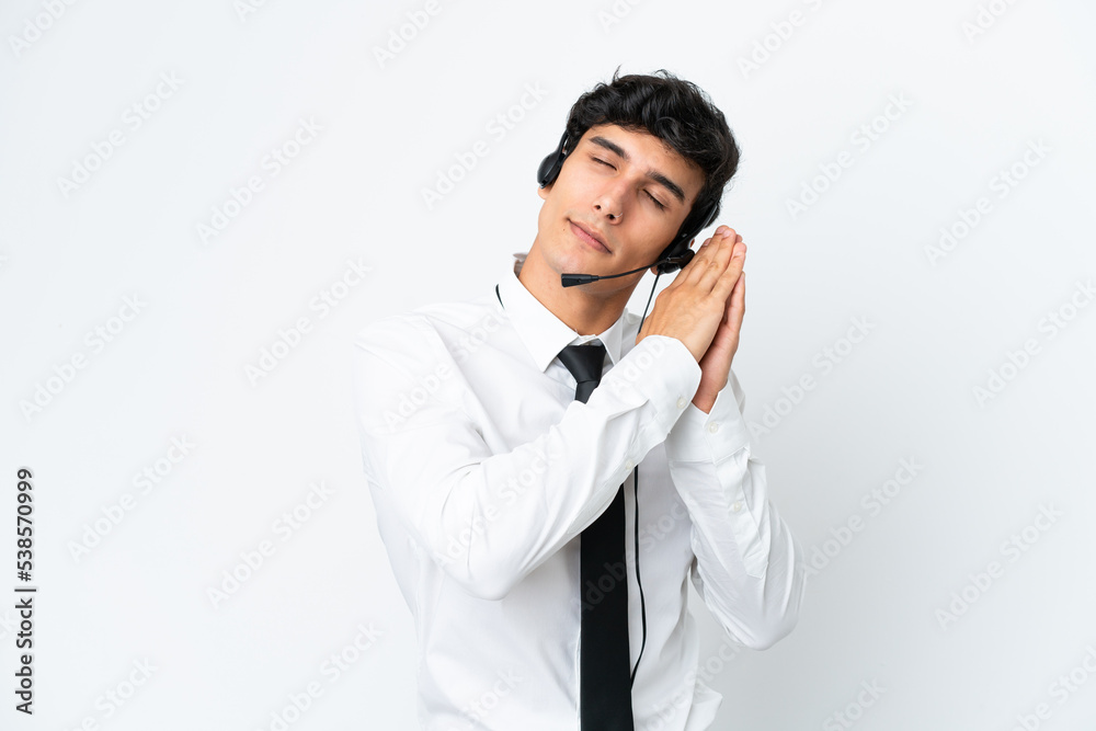 Telemarketer man working with a headset isolated on white background making sleep gesture in dorable expression Telemarketer man working with a headset isolated on white background making sleep gesture in dorable expression