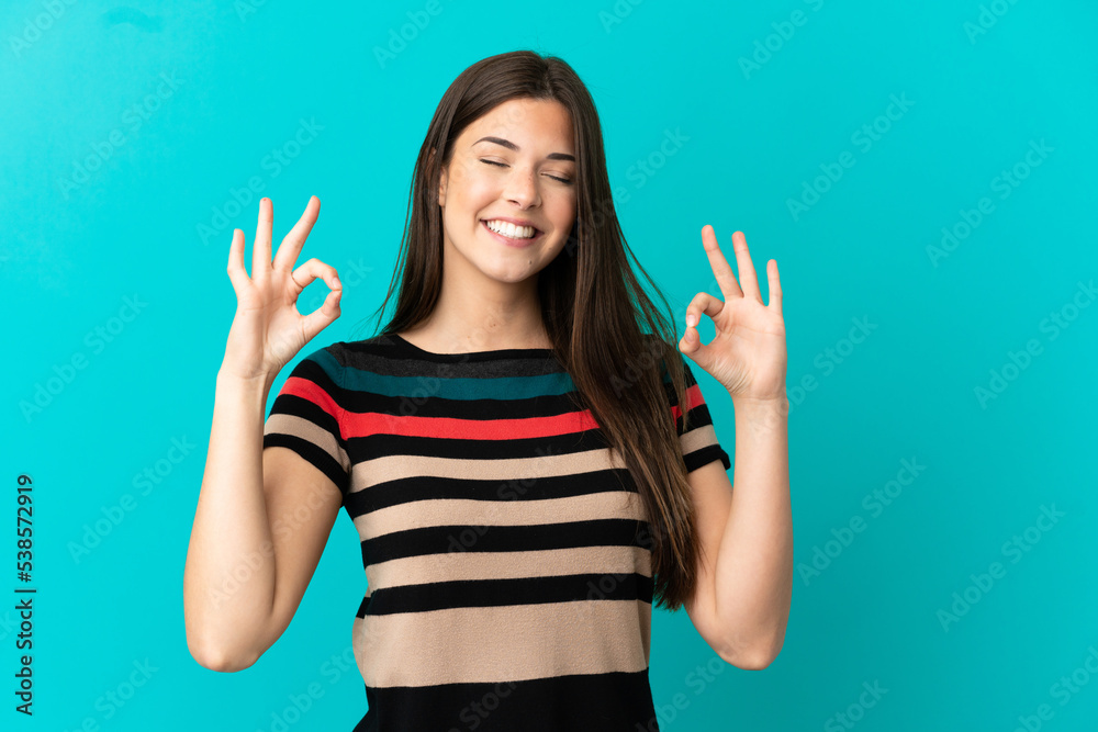 Teenager Brazilian girl over isolated blue background in zen pose Teenager Brazilian girl over isolated blue background in zen pose