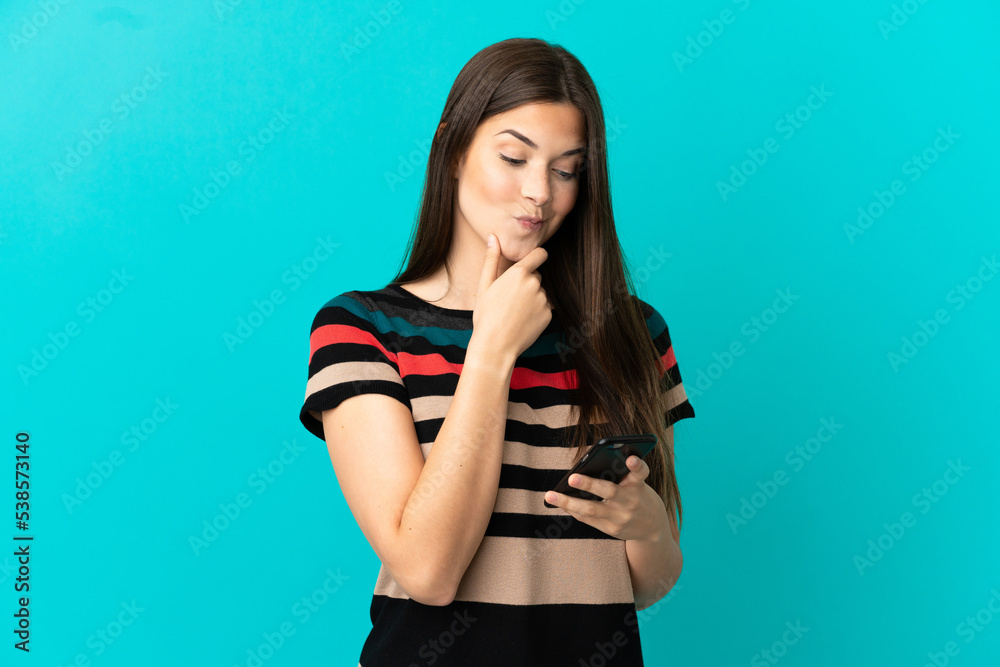 Teenager Brazilian girl over isolated blue background thinking and sending a message Teenager Brazilian girl over isolated blue background thinking and sending a message