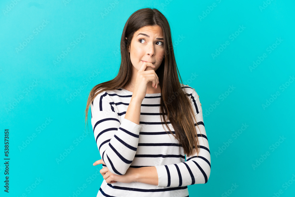 Teenager Brazilian girl over isolated blue background having doubts and thinking Teenager Brazilian girl over isolated blue background having doubts and thinking