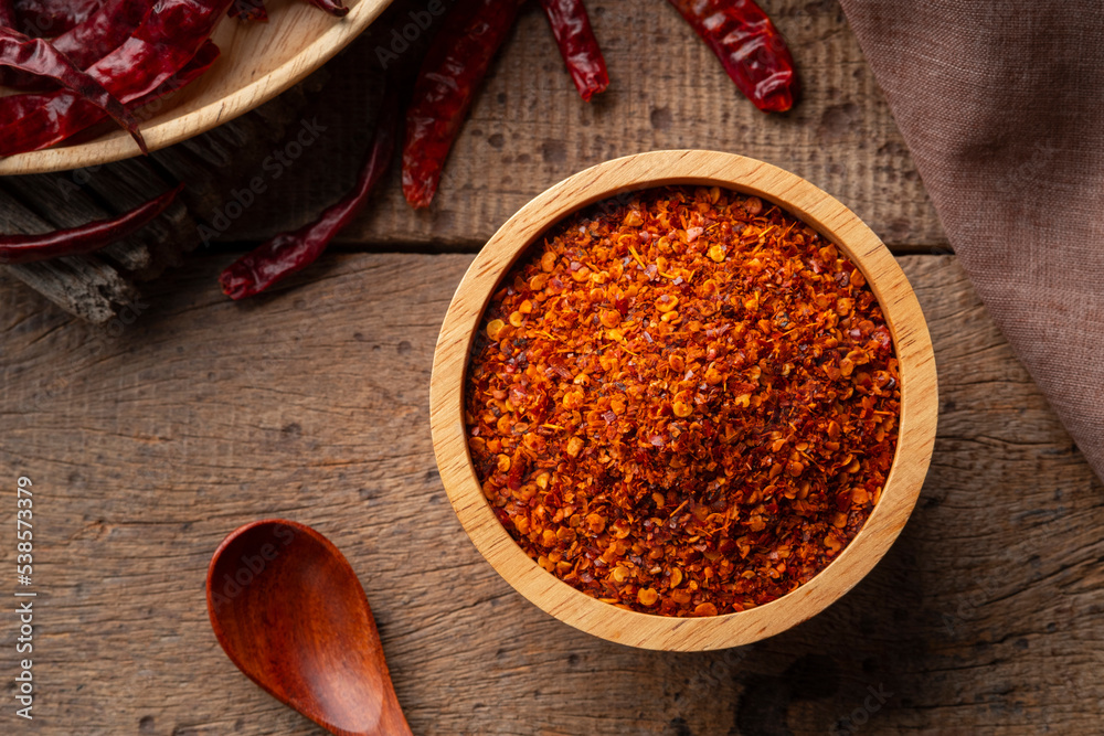 Dried red hot chilli powder in wooden bowl.Hot and spicy asian Condiments.Top view Dried red hot chilli powder in wooden bowl.Hot and spicy asian Condiments.Top view