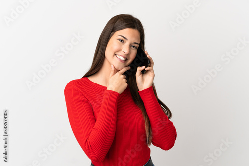 Teenager Brazilian girl using mobile phone over isolated white background happy and smiling