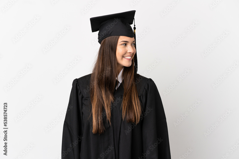 Teenager Brazilian university graduate over isolated white background looking to the side and smiling Teenager Brazilian university graduate over isolated white background looking to the side and smiling