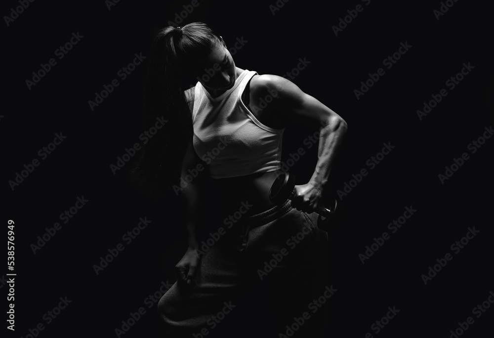 Athletic fitness woman posing in the studio on a dark background. Photo of an attractive woman in fashionable sportswear. Sports and healthy lifestyle