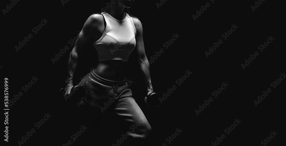 Athletic fitness woman posing in the studio on a dark background. Photo of an attractive woman in fashionable sportswear. Sports and healthy lifestyle