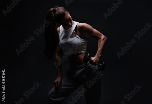 Athletic fitness woman posing in the studio on a dark background. Photo of an attractive woman in fashionable sportswear. Sports and healthy lifestyle © andy_gin