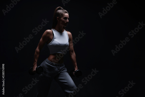 Athletic fitness woman posing in the studio on a dark background. Photo of an attractive woman in fashionable sportswear. Sports and healthy lifestyle