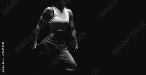 Fototapeta Naklejka Na Ścianę i Meble -  Athletic fitness woman posing in the studio on a dark background. Photo of an attractive woman in fashionable sportswear. Sports and healthy lifestyle