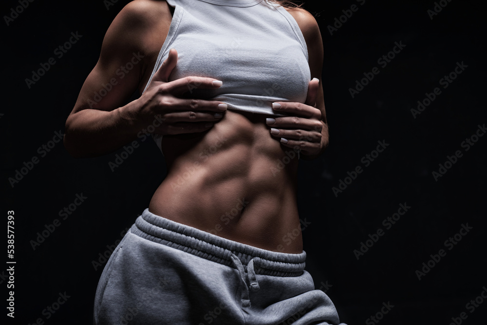 Athletic fitness woman posing in the studio on a dark background. Photo of an attractive woman in fashionable sportswear. Sports and healthy lifestyle - obrazy, fototapety, plakaty 