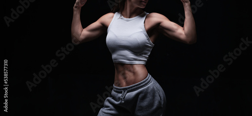 Athletic fitness woman posing in the studio on a dark background. Photo of an attractive woman in fashionable sportswear. Sports and healthy lifestyle