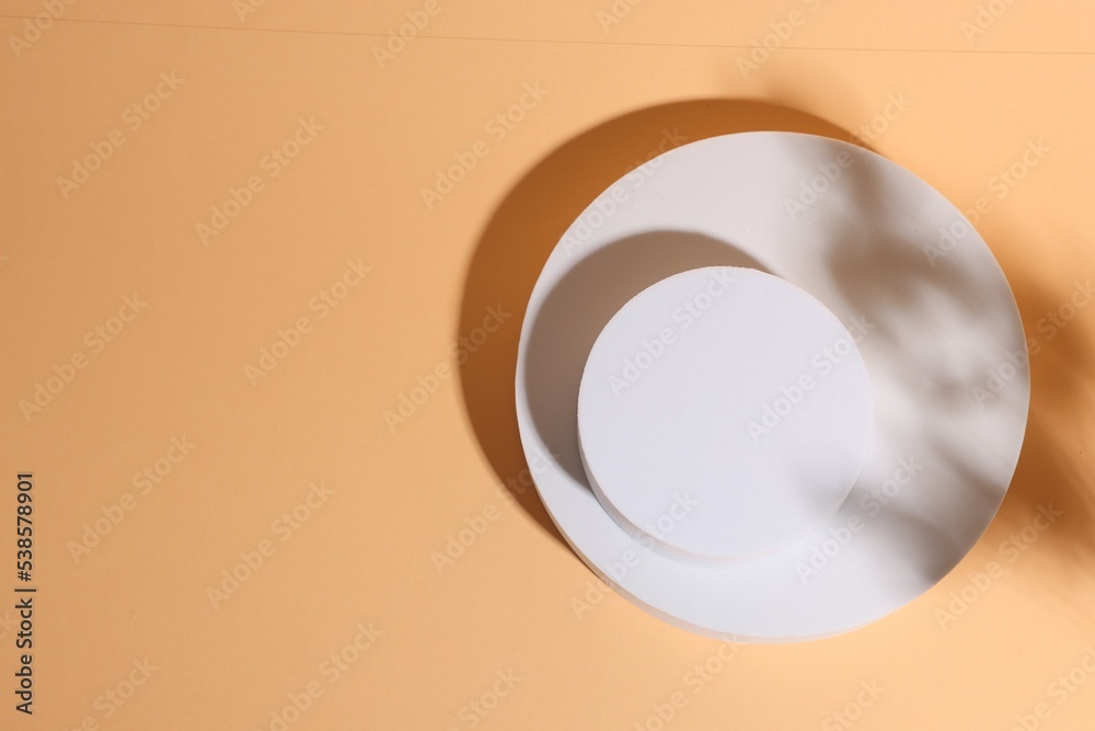 Round figures as podium for product presentation on pale orange background, top view. Space for text Round figures as podium for product presentation on pale orange background, top view. Space for text
