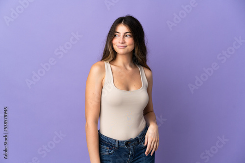 Young caucasian woman isolated on purple background having doubts while looking side