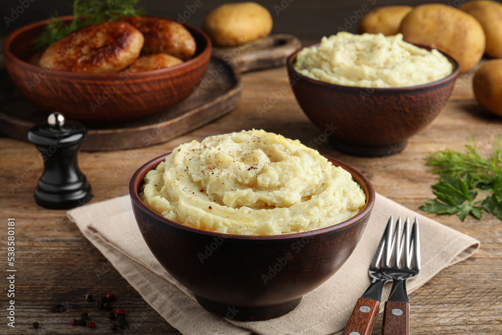 Bowl of tasty mashed potatoes with black pepper served on wooden table Bowl of tasty mashed potatoes with black pepper served on wooden table