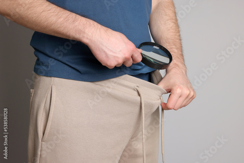 Tableau sur toile Man examining genital herpes with magnifying glass on beige background, closeup