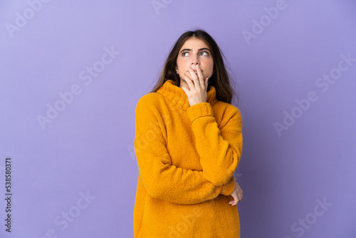 Young caucasian woman isolated on purple background having doubts and with confuse face expression