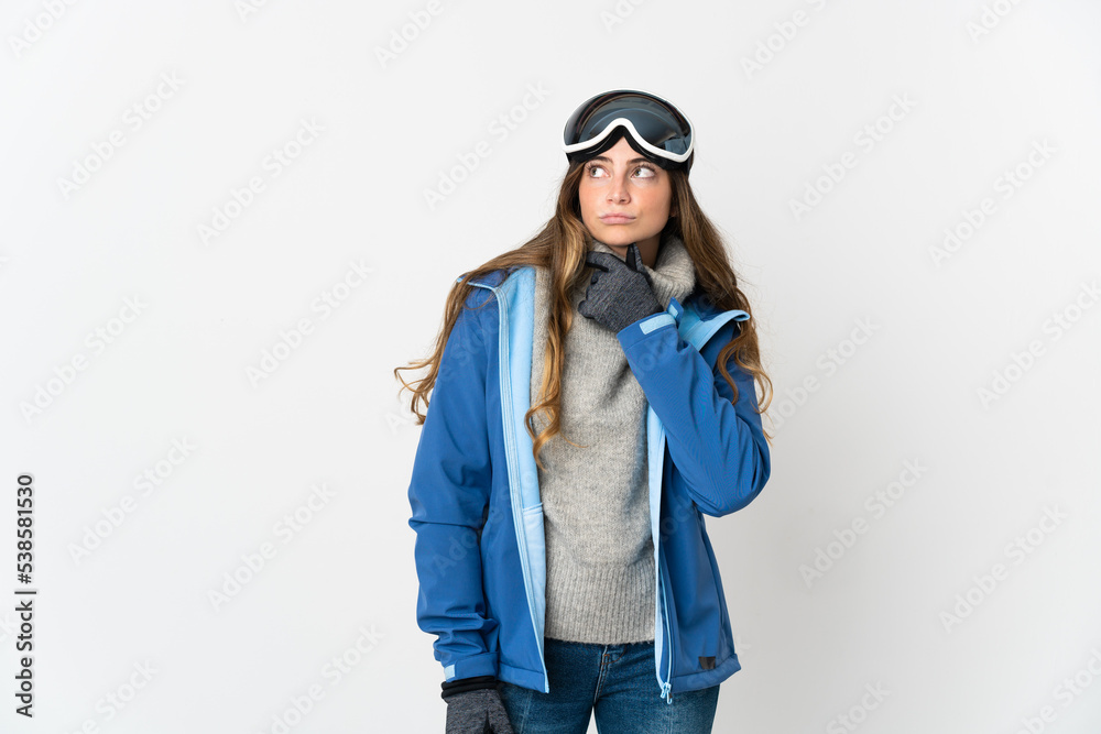 Skier girl with snowboarding glasses isolated on white background having doubts