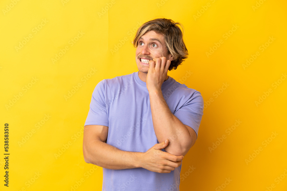 Handsome blonde man isolated on yellow background is a little bit nervous Handsome blonde man isolated on yellow background is a little bit nervous