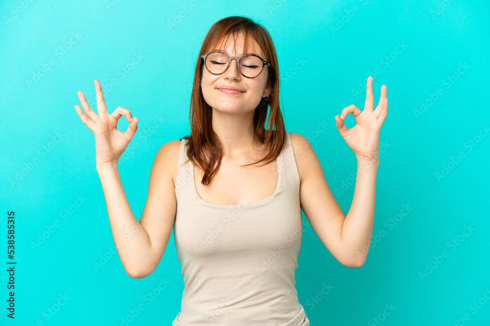 Redhead girl isolated on blue background in zen pose Redhead girl isolated on blue background in zen pose