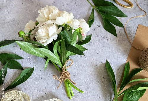 a woman makes a bouquet of peonies, a bouquet of kraft paper., pruning flowers, stylite makes a bouquet photo